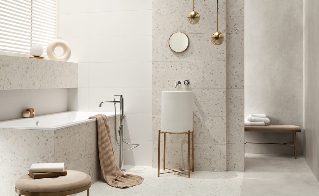 Terrazzo-tiled bathroom with a pedestal basin, brass pendant lights and a tiled bath surround