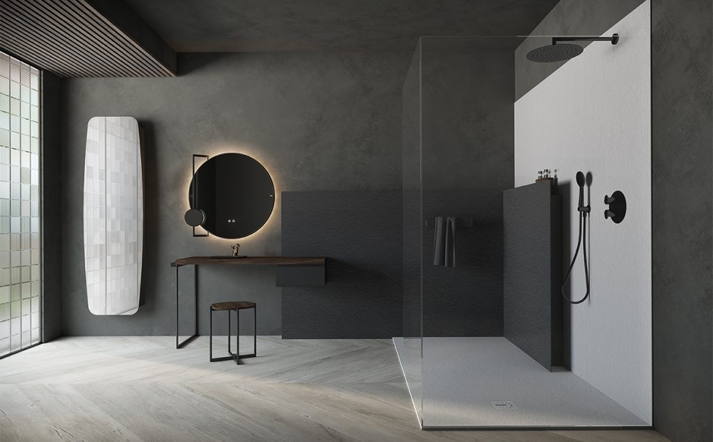Wet room-style shower with a fixed glass panel, dark grey stone-effect tiles and matt black brassware