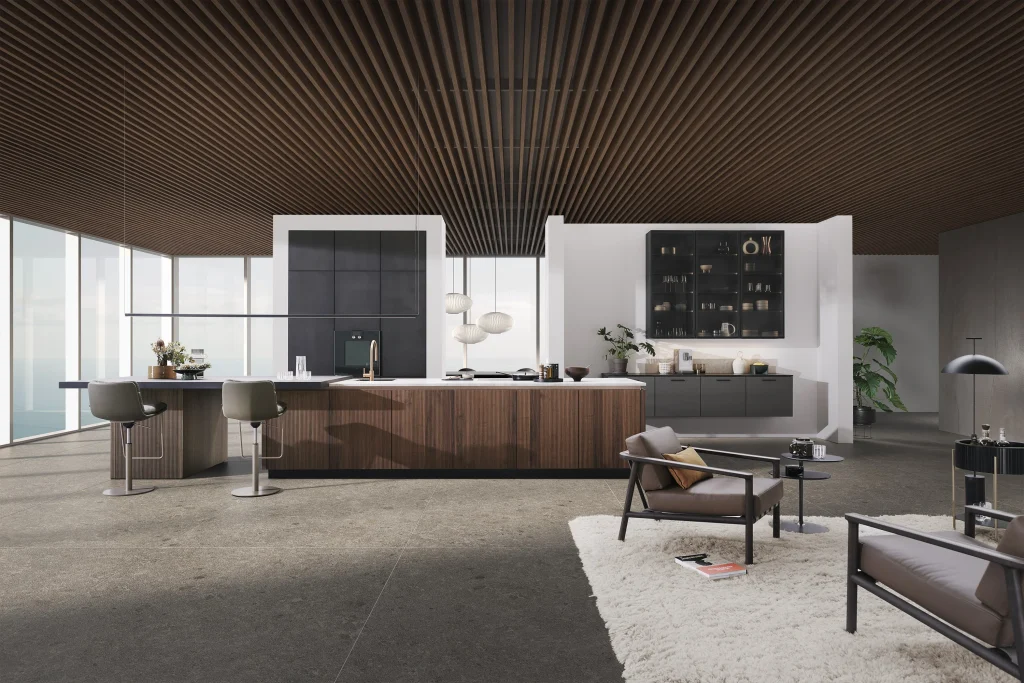 Large walnut kitchen island with seating at one end and a dark handleless tall bank behind, by Leicht